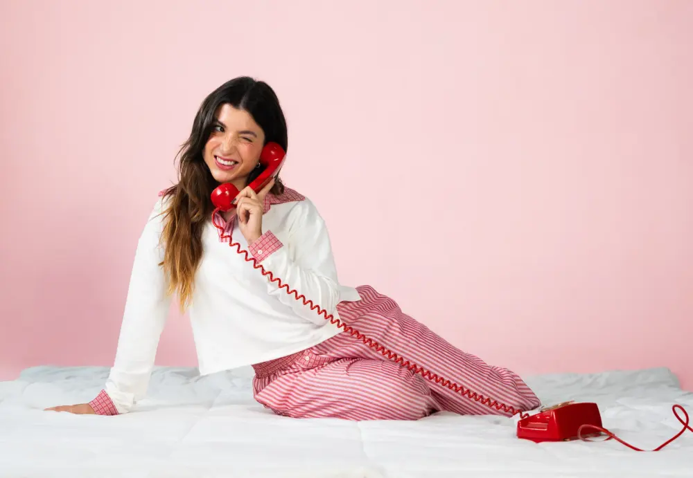 Model wearing a Frambô set and holding a red branded bag against a pink background.