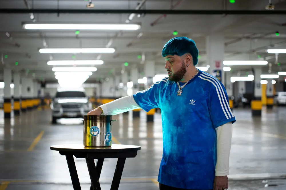 Artist standing beside a pot during a music video shoot.