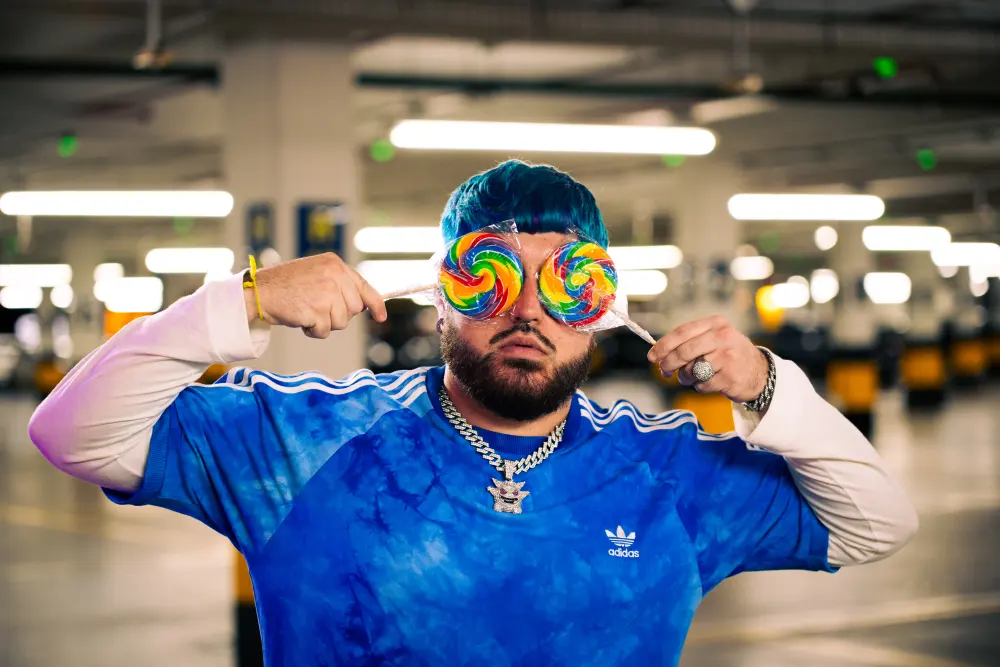 Artist holding lollipops in front of his eyes during a music video shoot.